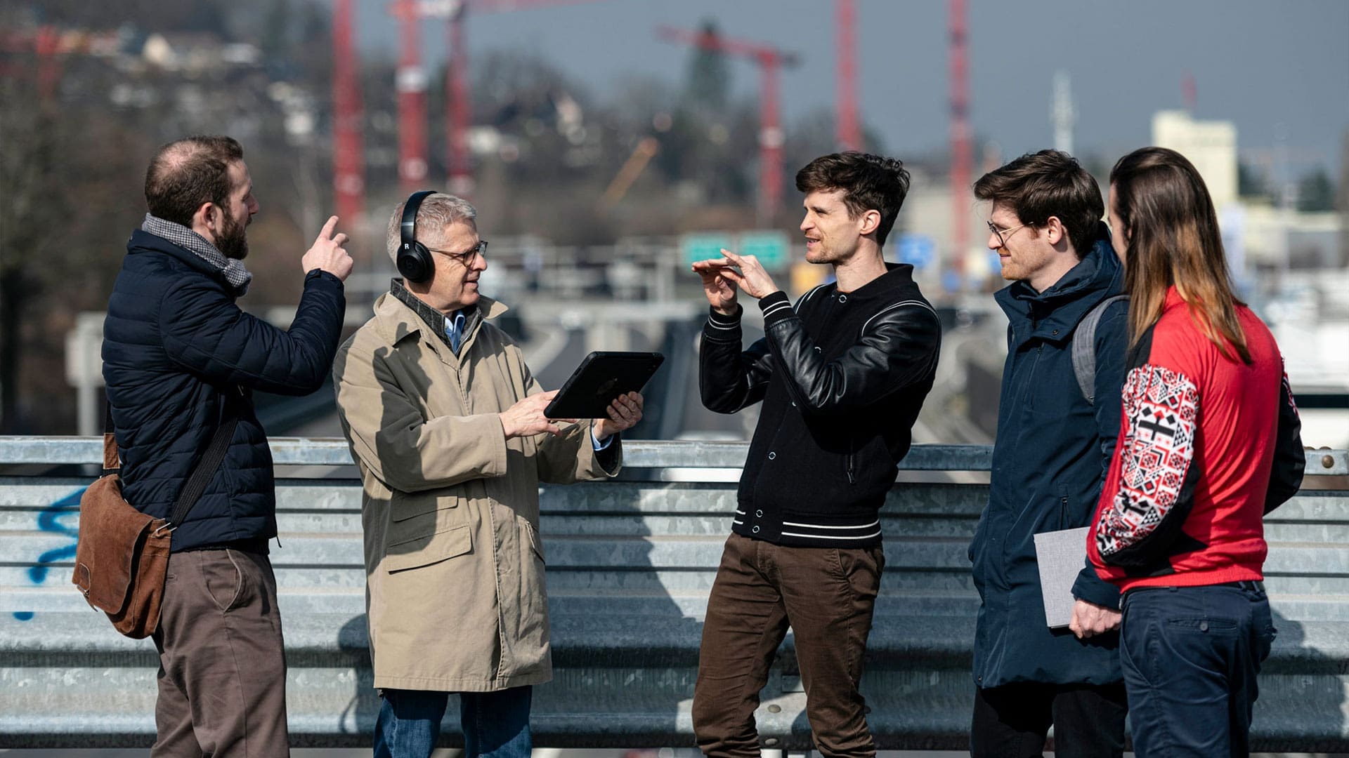 Gruppe von Menschen auf einer Autobahnbrücke diskutieren über eine Auralisation