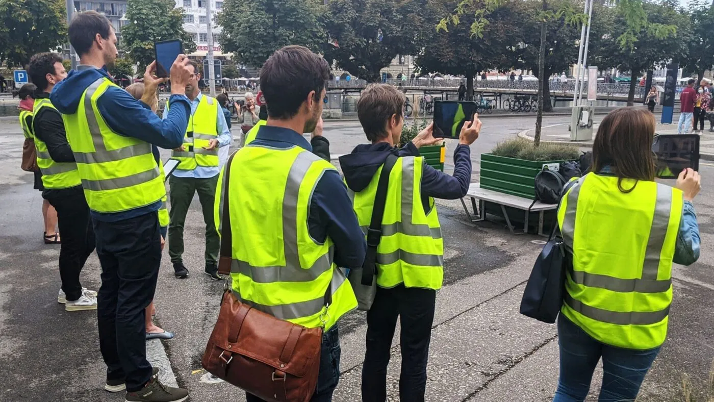 Eine Gruppe von Workshopteilnehmer:innen in Leuchtwesten testet die AR-Anwendung an der Bahnhofstrasse Luzern