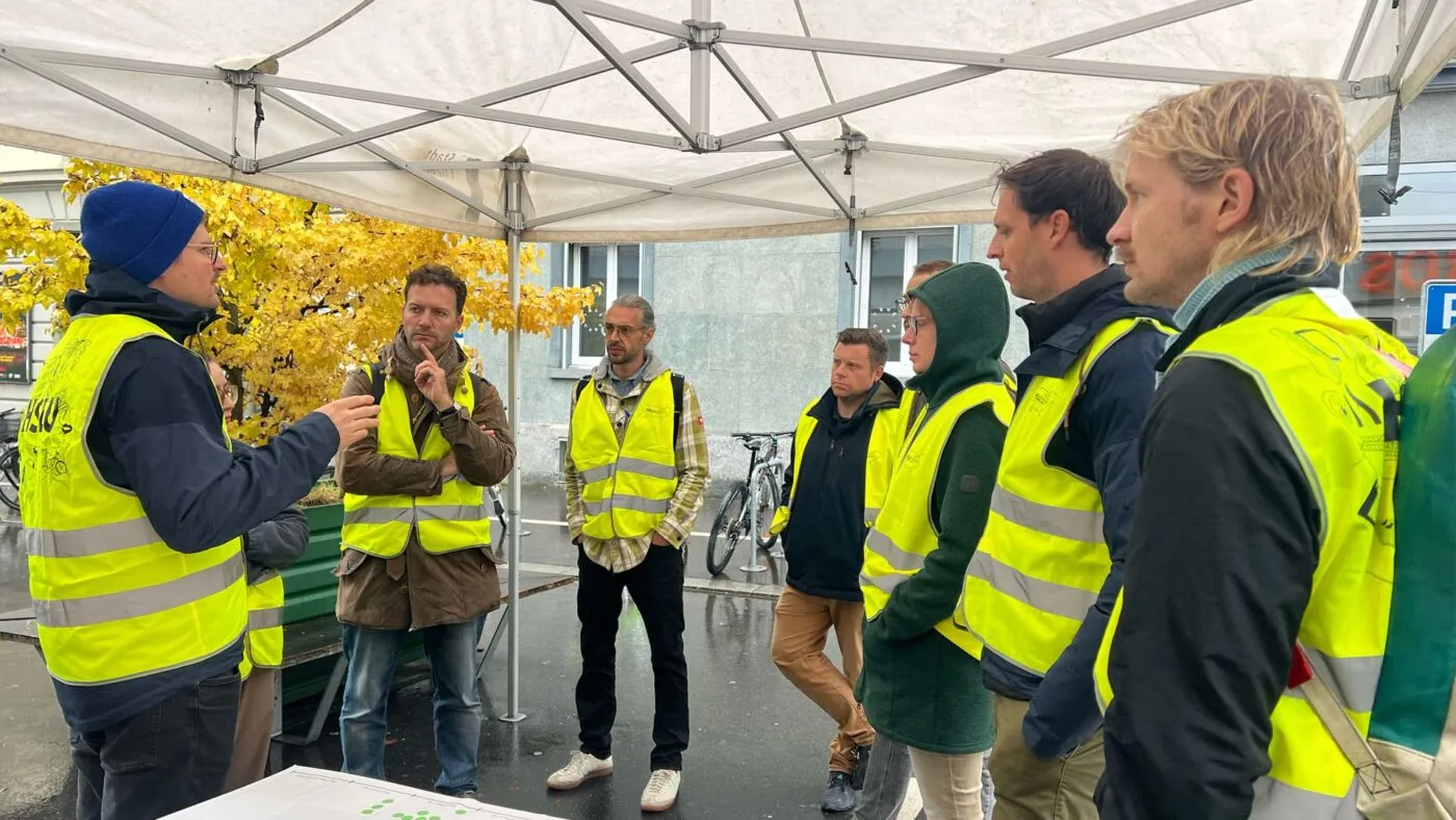 Workshopteilnehmer:innen in Leuchtwesten sprechen mit einer Person der HSLU über einen AR-Prototyp