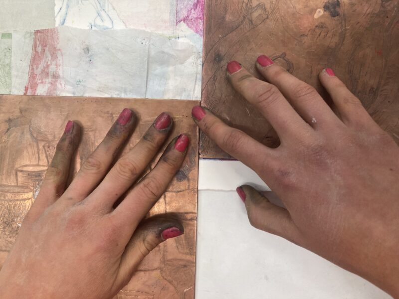 Kupferplatten und Hände mit rot lackierten Fingernägeln